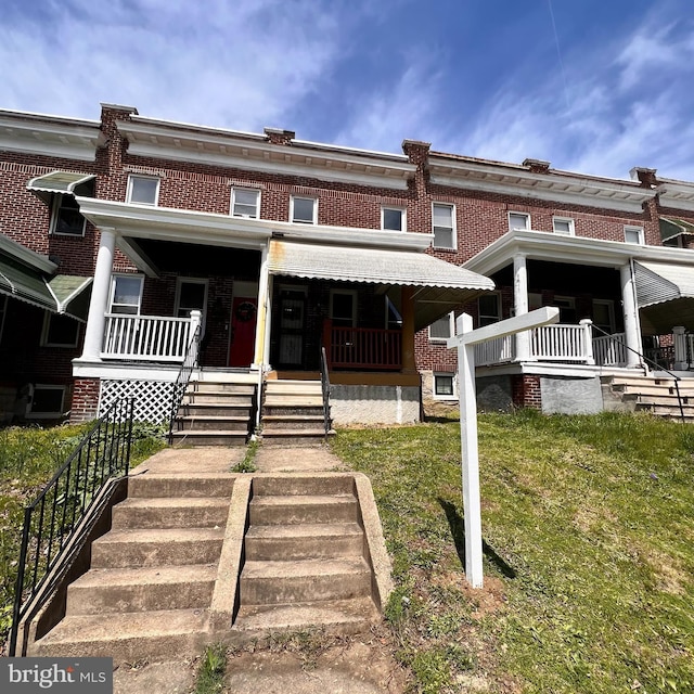 2328 W Lexington St, Baltimore, MD 21223 - townhome / multi-family property with a front lawn, brick siding, stairway, and covered porch