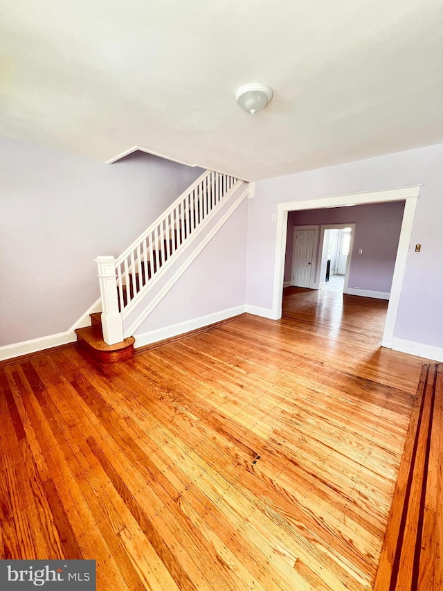 2328 W Lexington St, Baltimore, MD 21223 - unfurnished living room with stairway, baseboards, and hardwood / wood-style floors