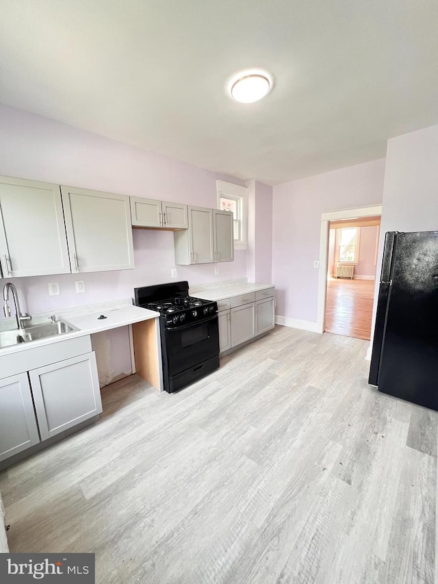 2328 W Lexington St, Baltimore, MD 21223 - kitchen featuring a sink, a healthy amount of sunlight, light wood-type flooring, gray cabinets, and black appliances