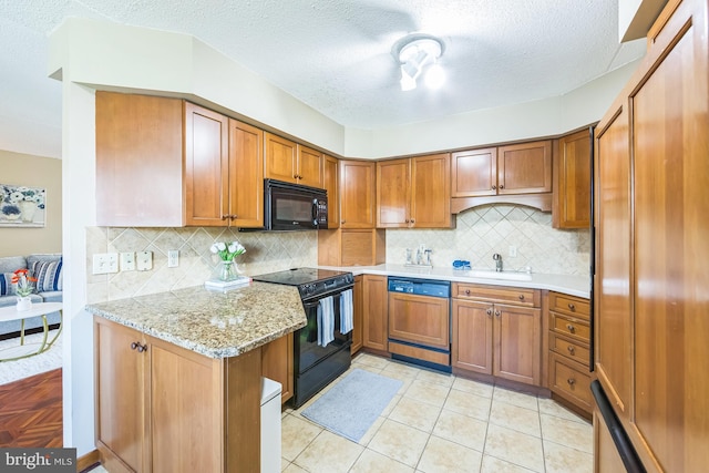 kitchen featuring tasteful backsplash, a sink, a textured ceiling, black appliances, and brown cabinets