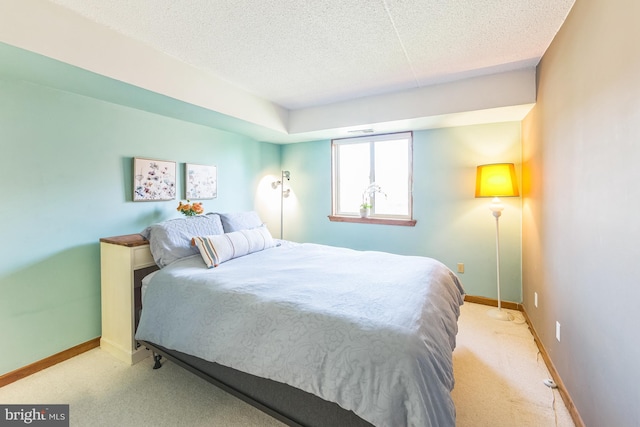 bedroom with light carpet, baseboards, and a textured ceiling