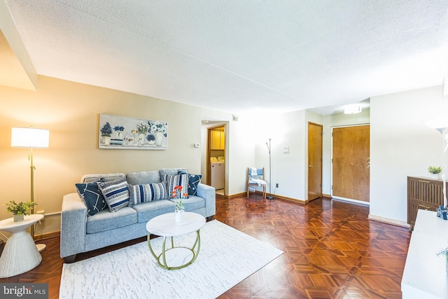 living area with baseboards, washer / dryer, and a textured ceiling