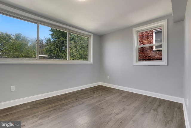 empty room with dark wood-style flooring and baseboards