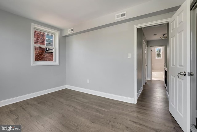 empty room featuring dark wood-style flooring, baseboards, and visible vents