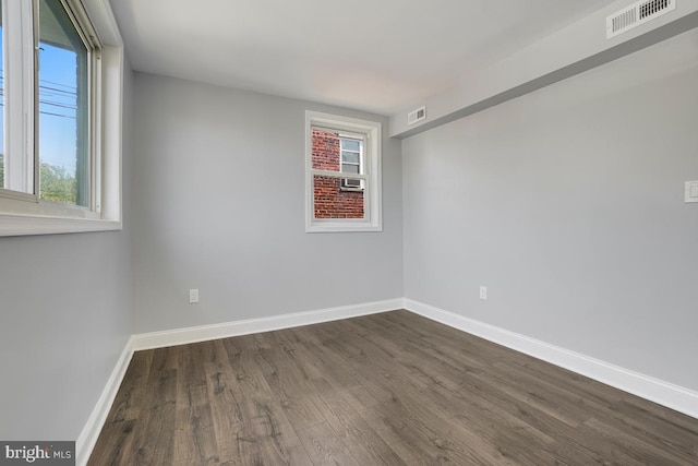 spare room with visible vents, baseboards, and dark wood-style floors