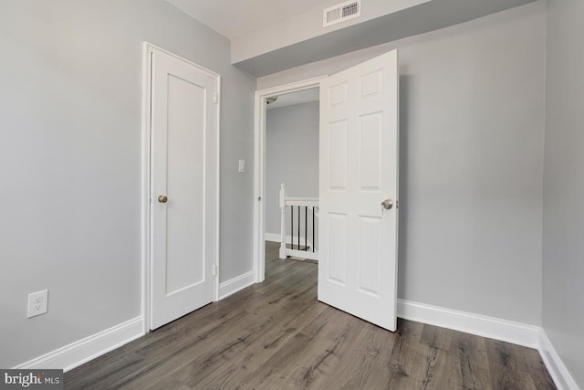 unfurnished bedroom featuring wood finished floors, baseboards, and visible vents
