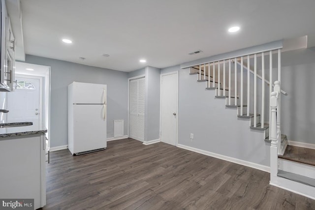 below grade area featuring a sink, visible vents, freestanding refrigerator, and dark wood finished floors