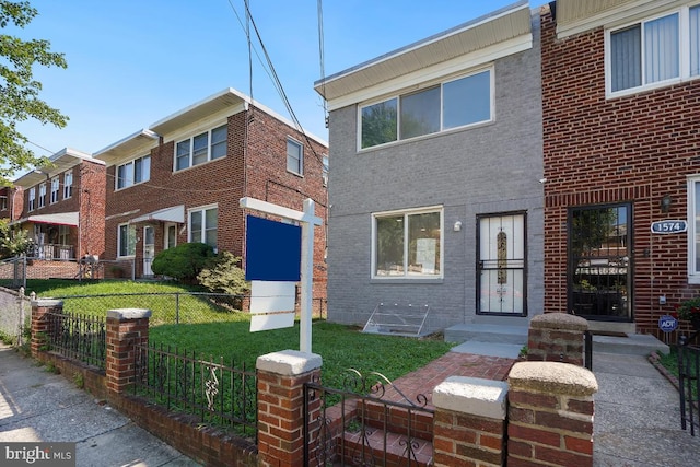 view of property featuring a front yard, fence, and brick siding