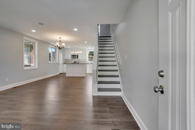 foyer entrance with stairs, dark wood-style flooring, baseboards, and an inviting chandelier