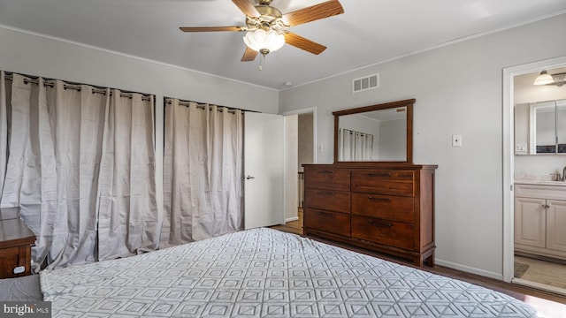 bedroom featuring visible vents, ensuite bathroom, a sink, crown molding, and wood finished floors