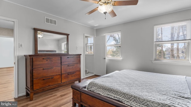 bedroom featuring ceiling fan, ornamental molding, visible vents, wood finished floors, and baseboards
