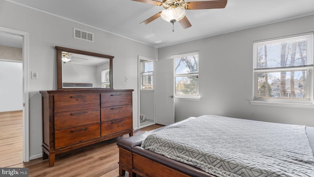 bedroom with baseboards, crown molding, a ceiling fan, visible vents, and wood finished floors