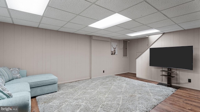 living room featuring wood finished floors, a drop ceiling, and electric panel