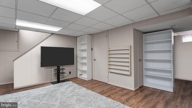 interior space featuring a paneled ceiling, baseboards, and wood finished floors