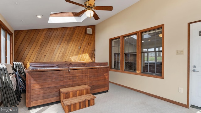 interior space with wood walls, ceiling fan, plenty of natural light, and carpet flooring