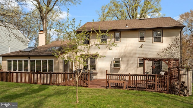 back of property featuring a pergola, a shingled roof, a wooden deck, and a lawn