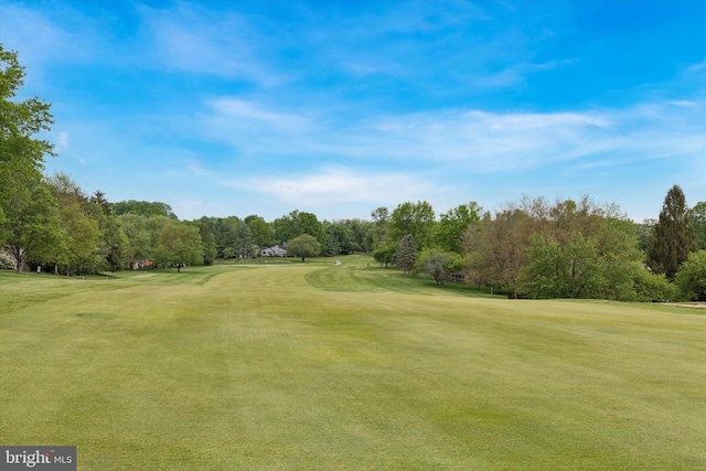view of home's community with view of wooded area, golf course view, and a lawn