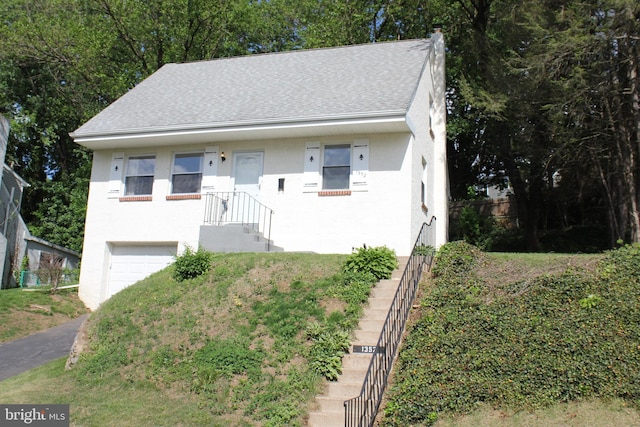 bungalow-style house with an attached garage, stucco siding, roof with shingles, and driveway