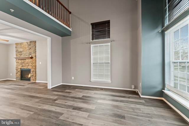 6319 Seton Ridge Dr, Baltimore, MD 21207 - unfurnished living room featuring wood finished floors, a fireplace, a towering ceiling, and baseboards