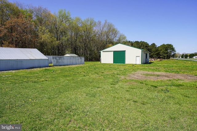 view of yard featuring driveway, an outdoor structure, an outbuilding, and a detached garage