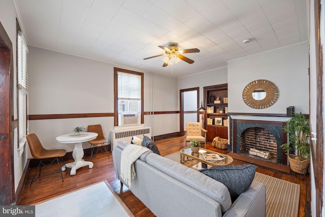 179 Green St, Annapolis, MD 21401 - living room with radiator, a fireplace, wood finished floors, a ceiling fan, and crown molding