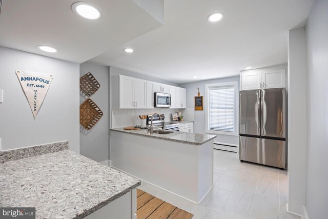 179 Green St, Annapolis, MD 21401 - kitchen featuring stainless steel appliances, a baseboard radiator, white cabinetry, a peninsula, and decorative backsplash
