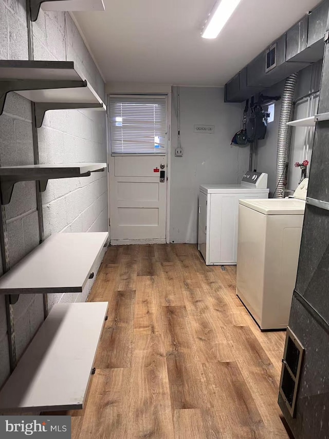 laundry area featuring laundry area, visible vents, concrete block wall, washer and dryer, and light wood finished floors