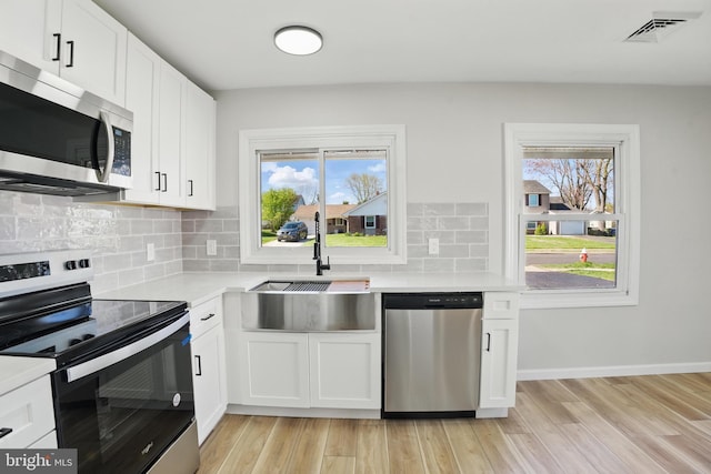 kitchen featuring visible vents, a sink, light countertops, light wood finished floors, and stainless steel appliances