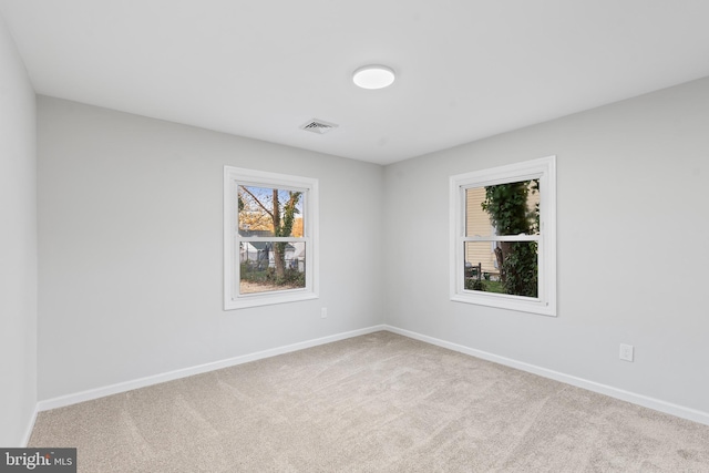 carpeted empty room featuring visible vents and baseboards