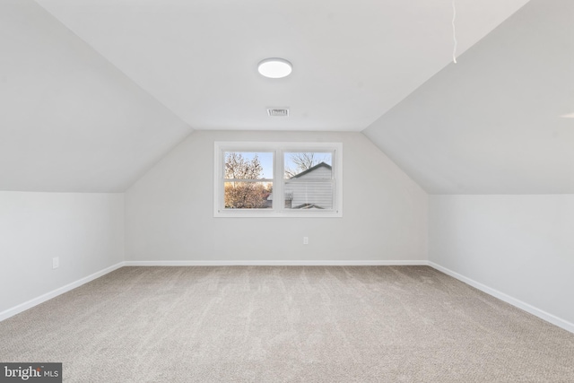 additional living space with visible vents, carpet, and vaulted ceiling