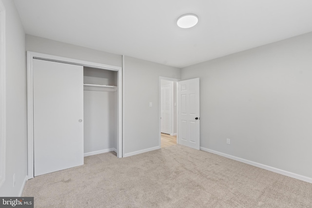 unfurnished bedroom with carpet floors, baseboards, and a closet