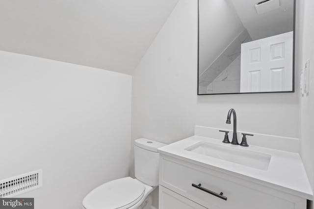 bathroom with visible vents, toilet, vanity, and vaulted ceiling