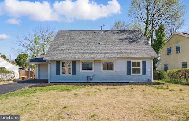 back of property with roof with shingles, a yard, and driveway
