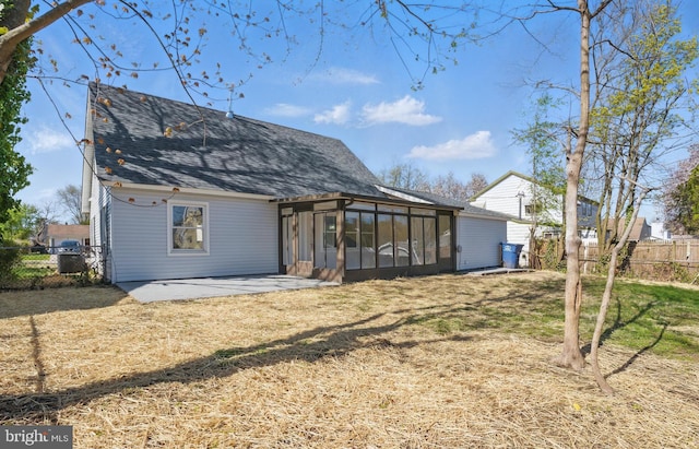 back of house with a sunroom, a yard, roof with shingles, a patio area, and fence