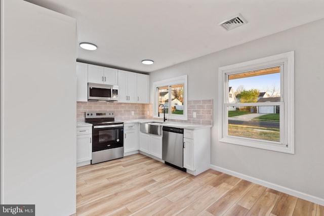 kitchen featuring white cabinetry, visible vents, light countertops, stainless steel appliances, and decorative backsplash