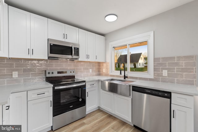 kitchen featuring a sink, light countertops, appliances with stainless steel finishes, and white cabinetry