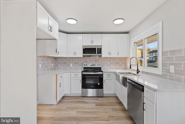 kitchen featuring a sink, light countertops, appliances with stainless steel finishes, and white cabinets