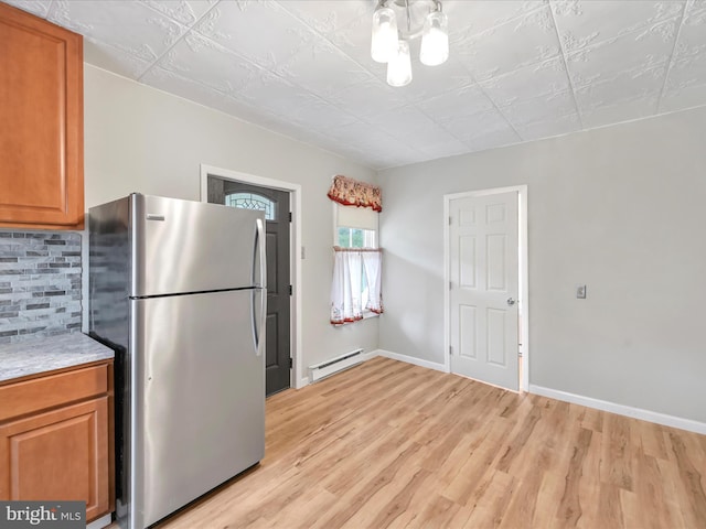 215 Biddle St, Gordon, PA 17936 - kitchen with a baseboard heating unit, light wood-style flooring, tasteful backsplash, freestanding refrigerator, and brown cabinets