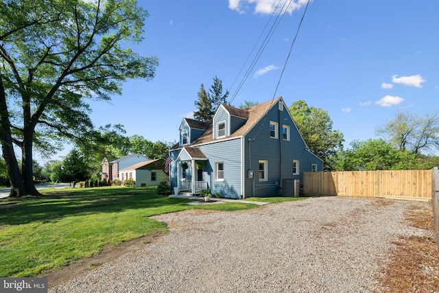 exterior space with central air condition unit, fence, driveway, and a front lawn