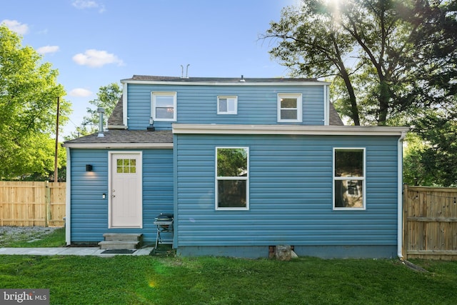 rear view of house featuring fence, a yard, and entry steps