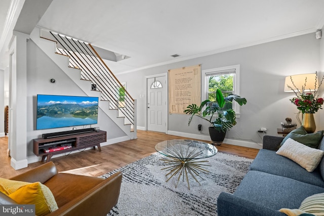 living area featuring crown molding, wood finished floors, and stairway