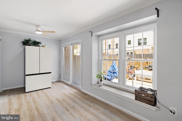 unfurnished room featuring baseboards, a ceiling fan, wood finished floors, and crown molding