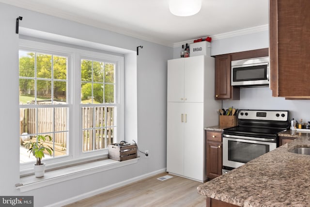kitchen with crown molding, light wood-type flooring, stone counters, appliances with stainless steel finishes, and visible vents