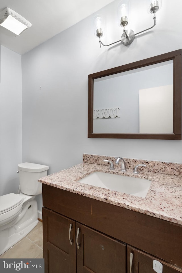 half bath with toilet, vanity, and tile patterned floors