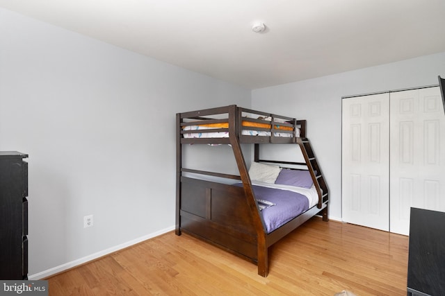 bedroom with light wood-style flooring, a closet, and baseboards
