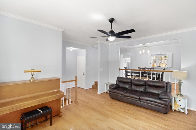 living area featuring baseboards, a ceiling fan, wood finished floors, stairway, and ornamental molding