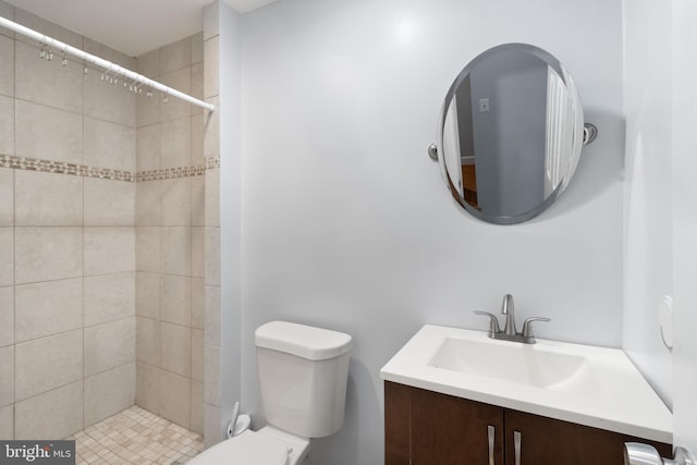 full bath with a tile shower, vanity, and toilet