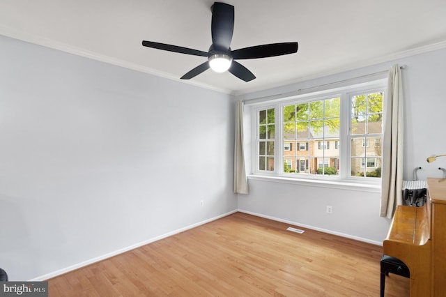 spare room with light wood-style floors, ceiling fan, baseboards, ornamental molding, and visible vents