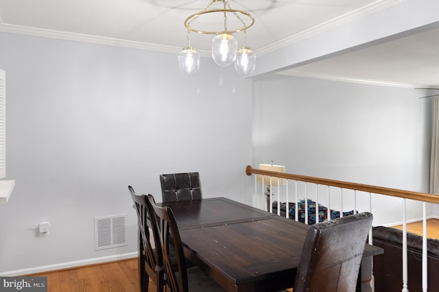 dining room featuring baseboards, crown molding, wood finished floors, and visible vents