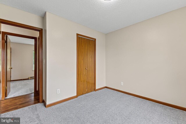 392 Walker Way, Timberville, VA 22853 - unfurnished bedroom with carpet floors, baseboards, baseboard heating, a closet, and a textured ceiling